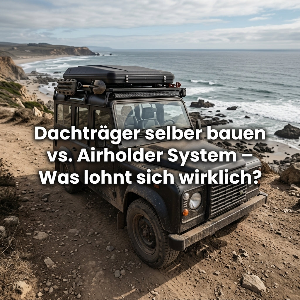 Klassischer schwarzer Geländewagen an einer felsigen Küste mit Dachbox, Offroad-Zubehör und Dachträgersystem. Groß eingeblendeter Text: „Dachträger selber bauen vs. Airholder System – Was lohnt sich wirklich?“