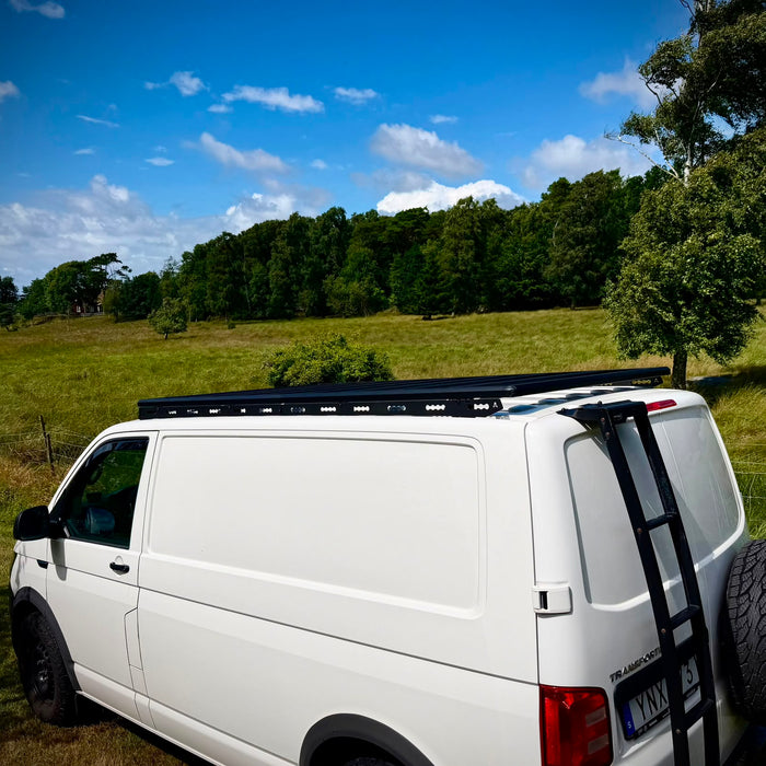 VW Transporter T6 mit Airholder Dachträgersystem und Heckleiter auf einer grünen Wiese