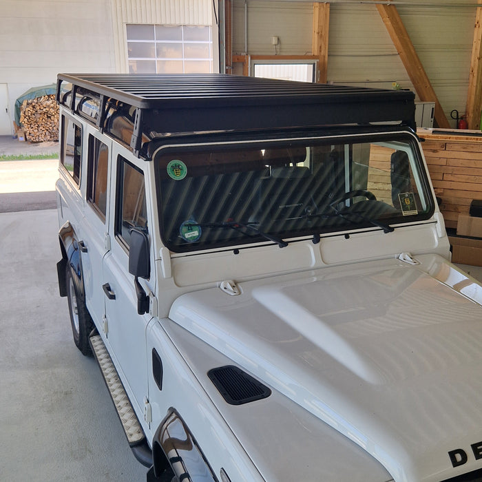 Frontansicht der modularen Airholder Dachträger-Plattform aus schwarzem Aluminium auf einem Defender Geländewagen