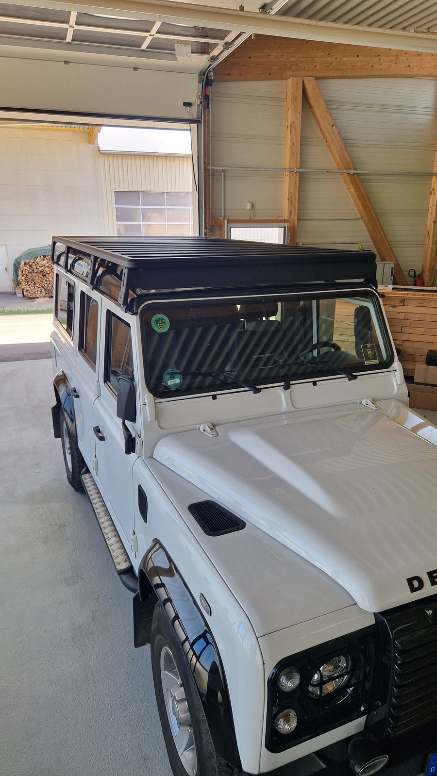 Frontansicht der modularen Airholder Dachträger-Plattform aus schwarzem Aluminium auf einem Defender Geländewagen