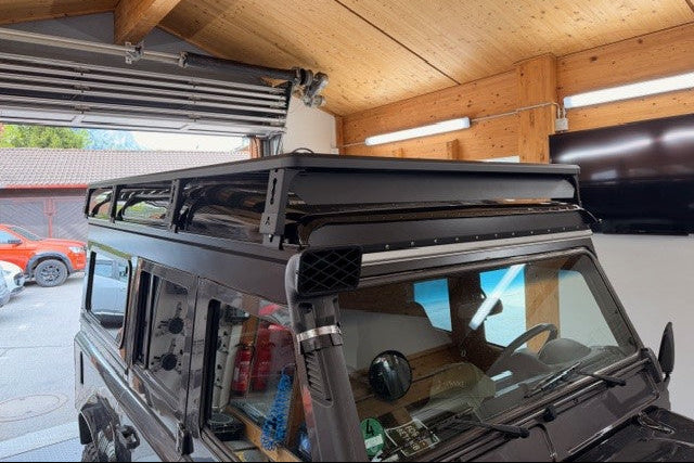 Nahaufnahme eines schwarzen Dachträgers mit integriertem Windabweiser auf einem Land Rover Defender_Airholder