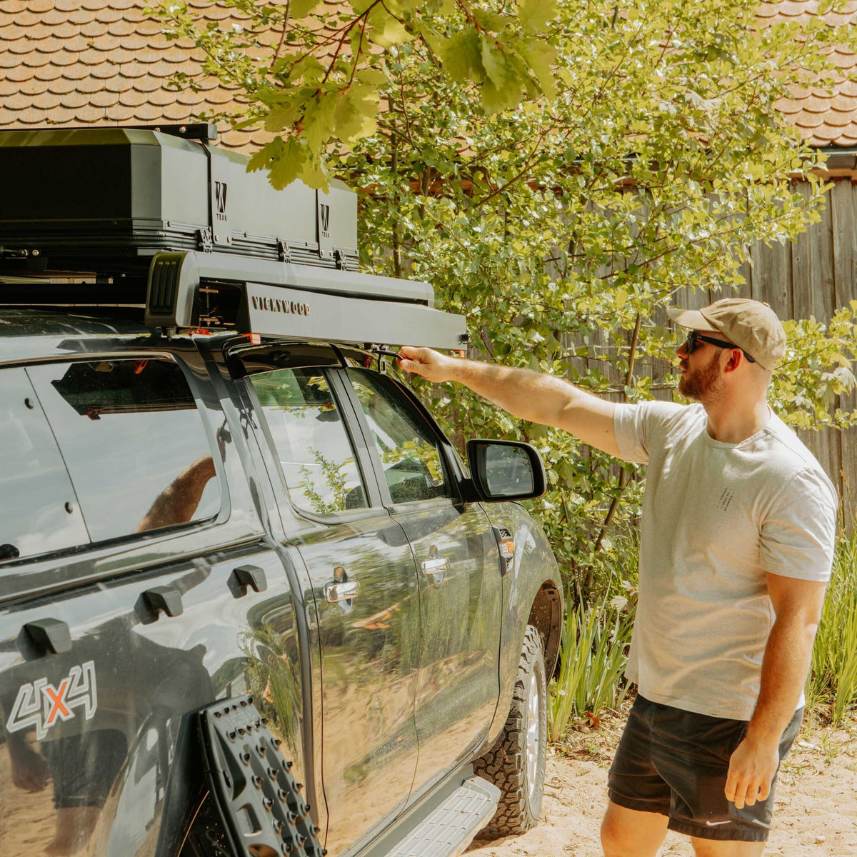 Mann zieht die VICKYWOOD Seitenmarkise BRANCH AUTOMATIC 2M an einem Pick-up mit Dachträger von Hand aus